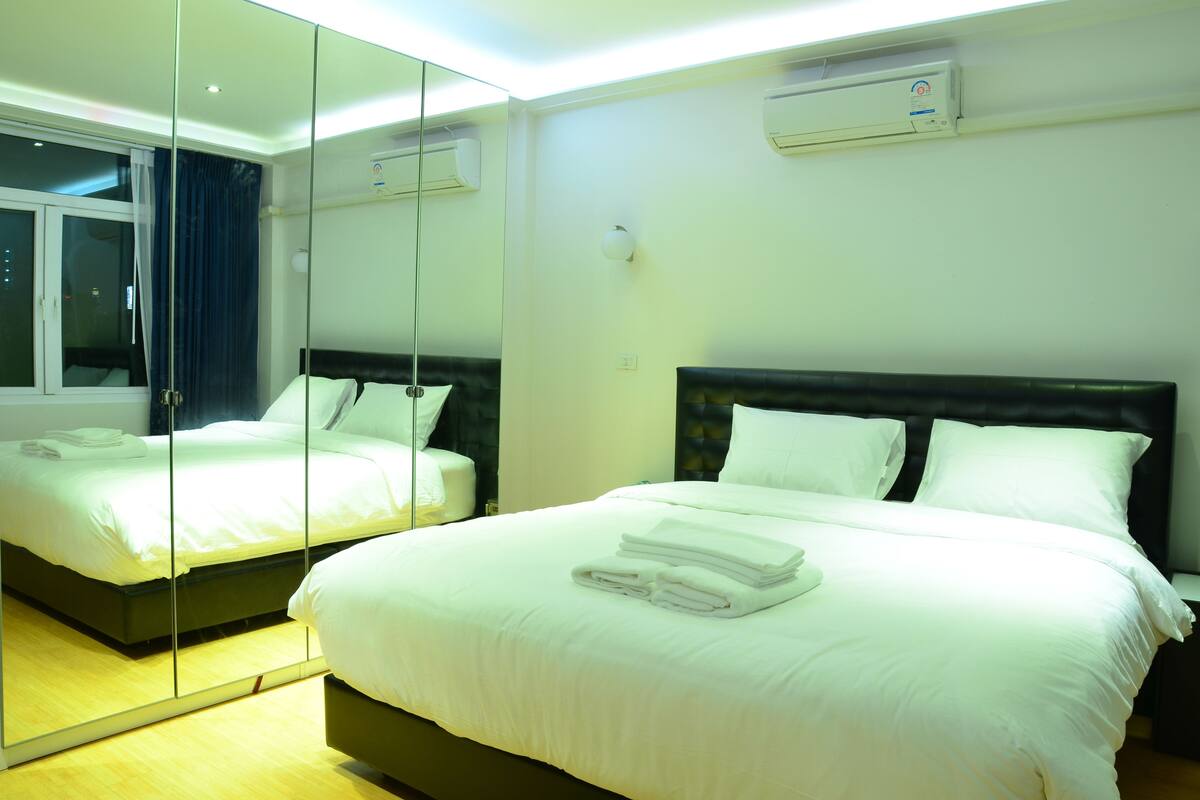 Ein Hotelzimmer mit zwei Betten, einem großen Spiegel und einer Klimaanlage an der Wand.