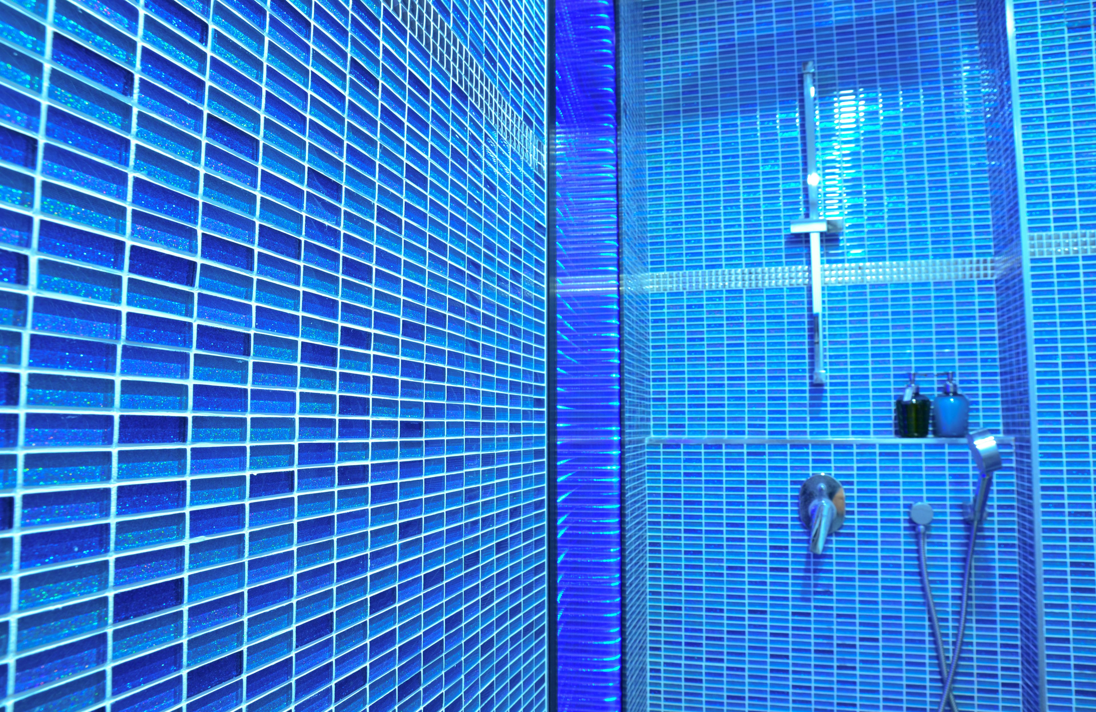 A bathroom with blue-tinted glass tiles and modern fixtures.