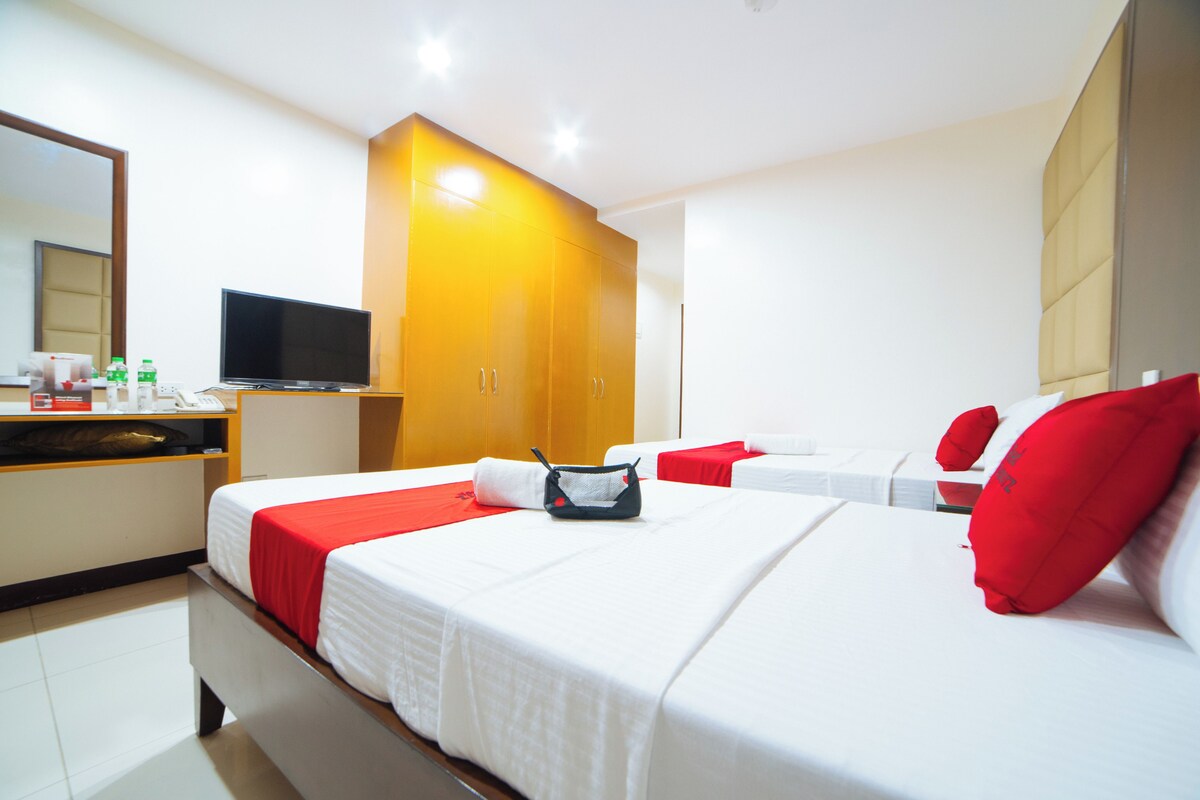 Une chambre d’hôtel avec deux lits, une télévision, un minibar et un grand miroir.