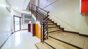 Un intérieur moderne comprenant un escalier, un comptoir d’accueil et un panneau de commande fixé au mur.