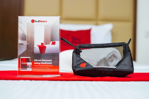 A promotional display for RedDoorz with a direct discount offer, a black mesh bag, and a red and white bedspread.
