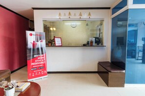 A reception area with a RedDoorz sign, a clock, and a window with a view of the outside. - Reddoorz @ Bonifacio St Cebu (Cebu City)