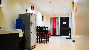 A compact kitchen with a refrigerator, water dispenser, and a dining area with chairs and a table. - RedDoorz Plus @ Mabolo Cebu (Cebu City)