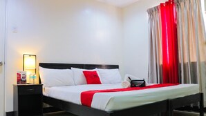 A neatly made bed with white and red bedding, a bedside table with a lamp, and a red curtain. - RedDoorz Plus @ Mabolo Cebu (Cebu City)