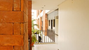 A corridor with a tiled floor, a brick wall, and a metal railing. - RedDoorz Plus @ Mabolo Cebu (Cebu City)