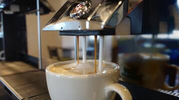 En kaffemaskin som brygger espresso och fyller det i en vit kopp.