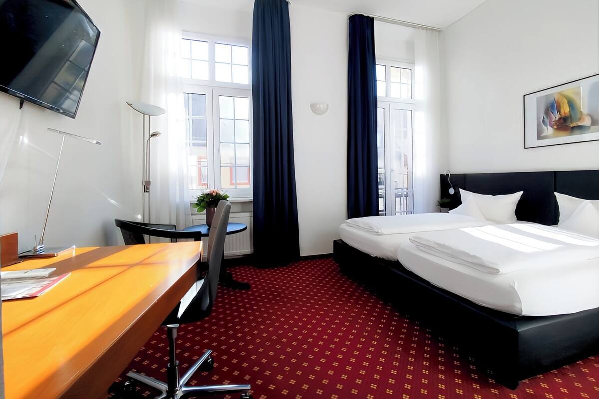 Una habitación de hotel con cama, escritorio, silla y televisor.