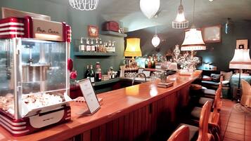 A bar area with a popcorn machine, shelves with bottles, and hanging lights.