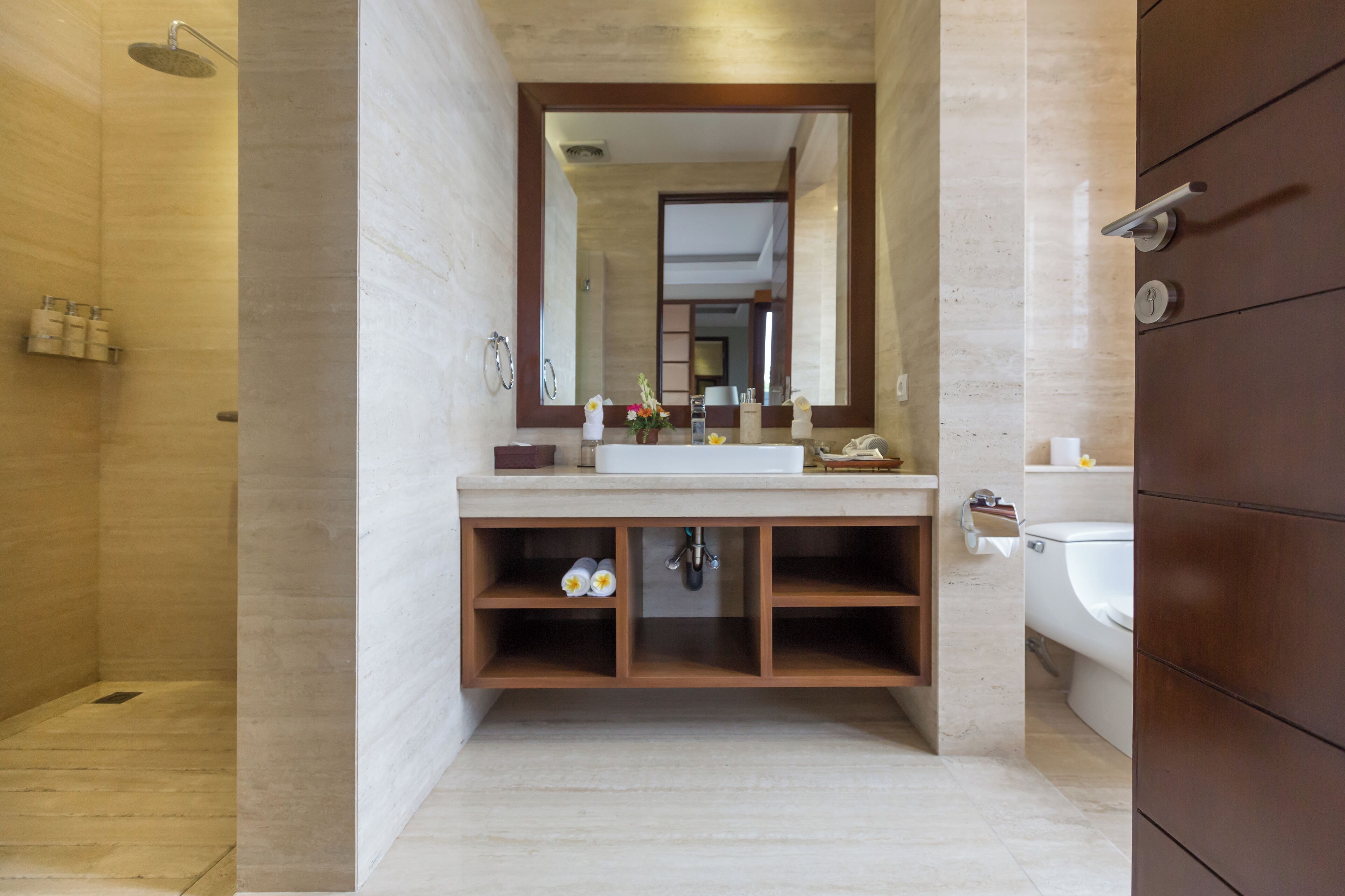 Un baño moderno con tocador de madera, un espejo grande y una ducha.