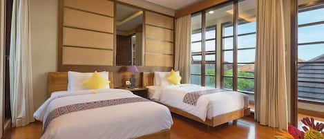 A hotel room with two beds, wooden flooring, large windows, and a view of the outdoors.