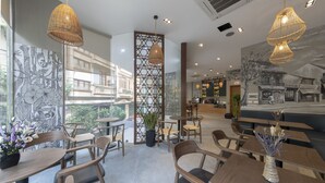 Un café moderne avec des meubles en bois, de grandes fenêtres et des œuvres d’art décoratives sur les murs.