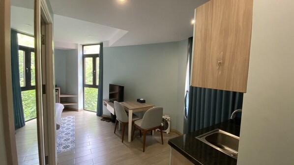 A compact kitchen with a dining area, a built-in TV, and a large window.
