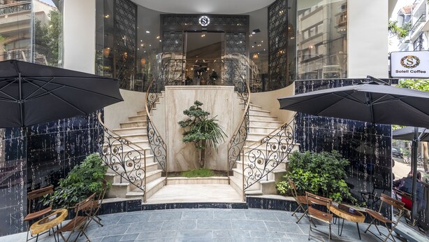 Un intérieur moderne avec un escalier, des murs recouverts de carreaux noirs et une plante au centre.