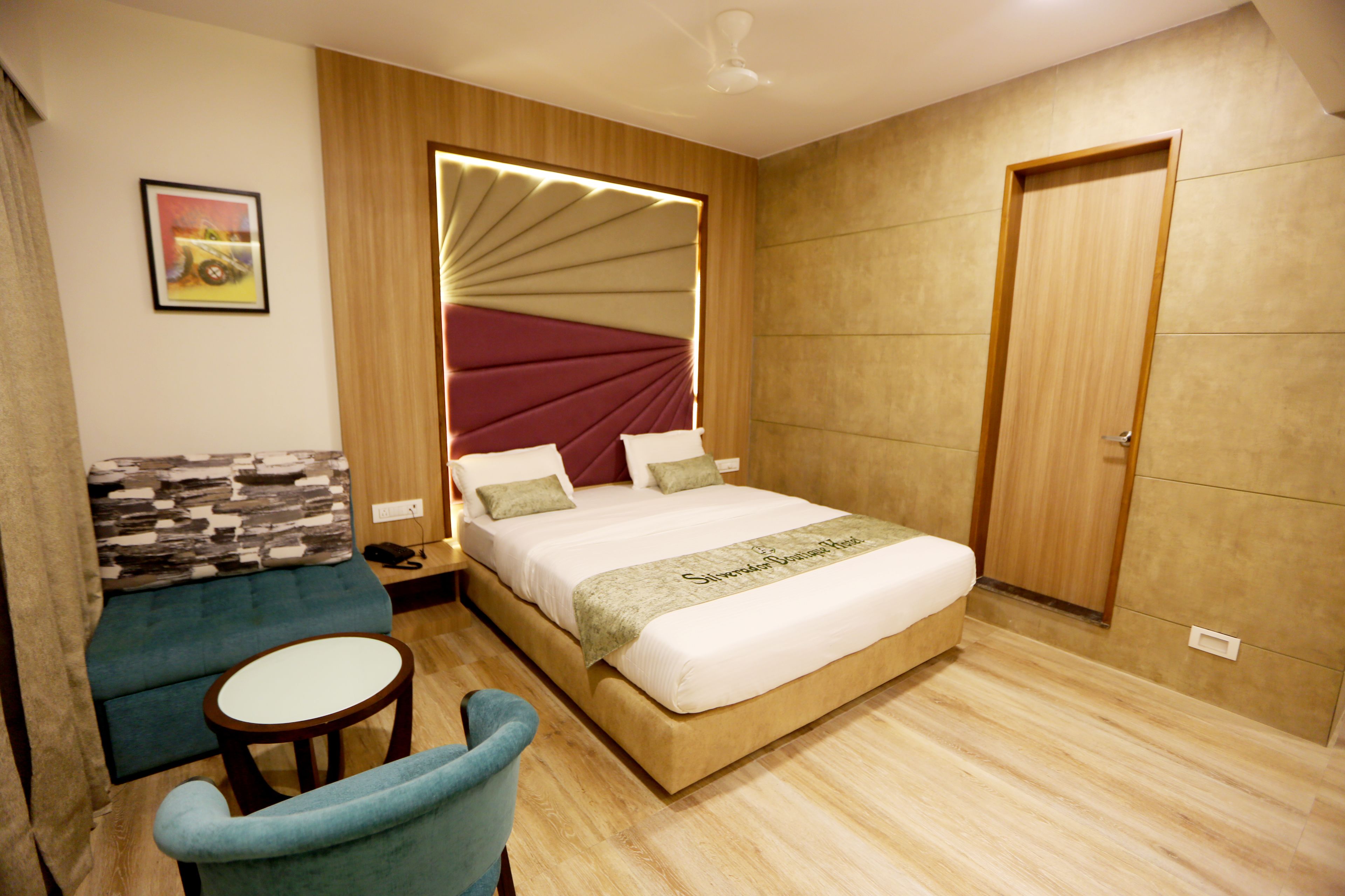 Una habitación de hotel moderna con una cama grande, un sofá, una mesita y una puerta.