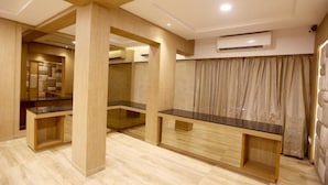 A modern hotel room with a wooden floor, a central glass partition, and a built-in bench.
