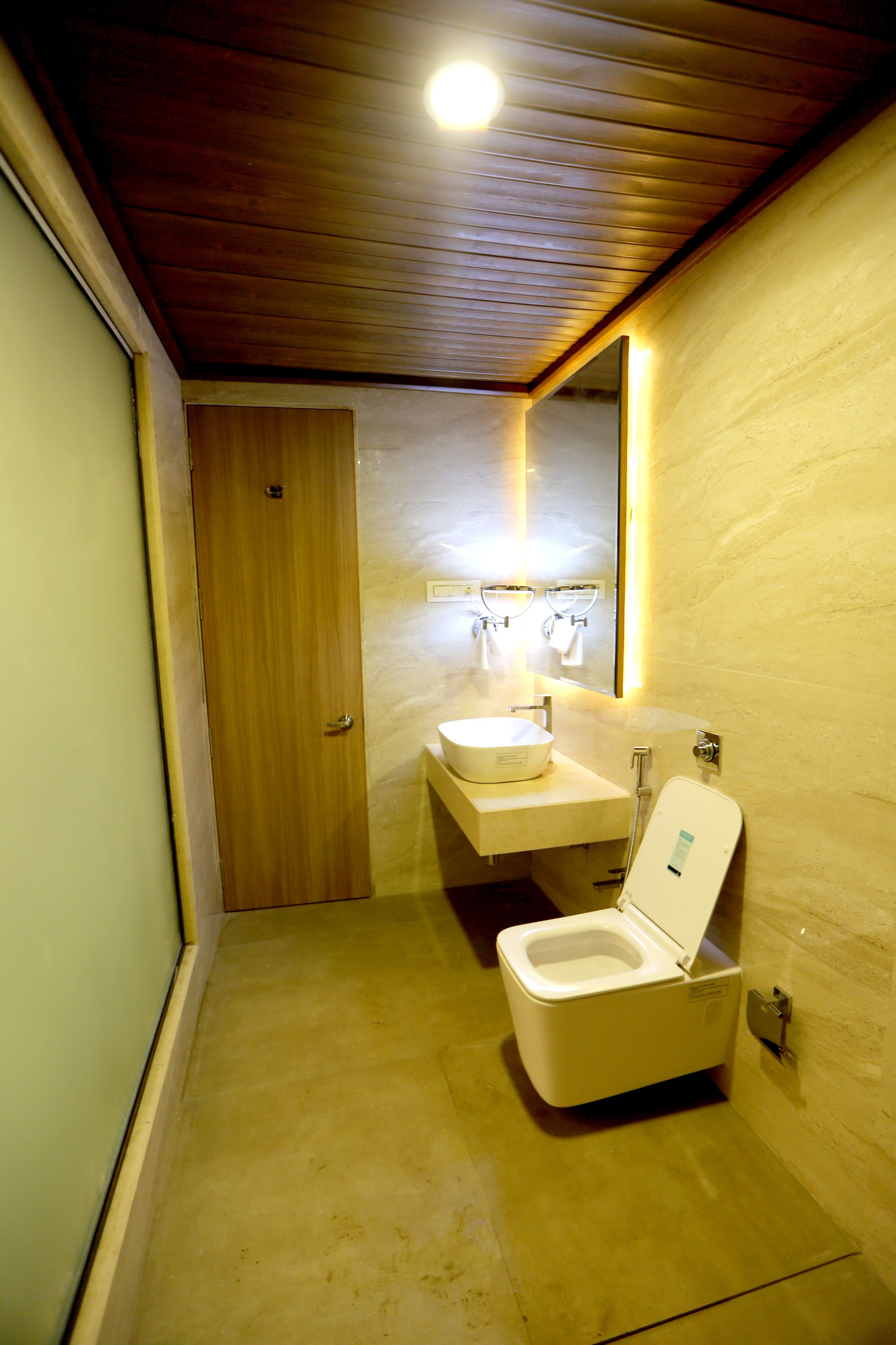 A compact bathroom with a wooden ceiling, a toilet, and a sink.