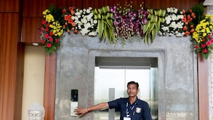A man standing in front of an elevator with a Buddha statue to the left.