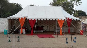 A large tent with a stage, red curtains, and lanterns on the ground.