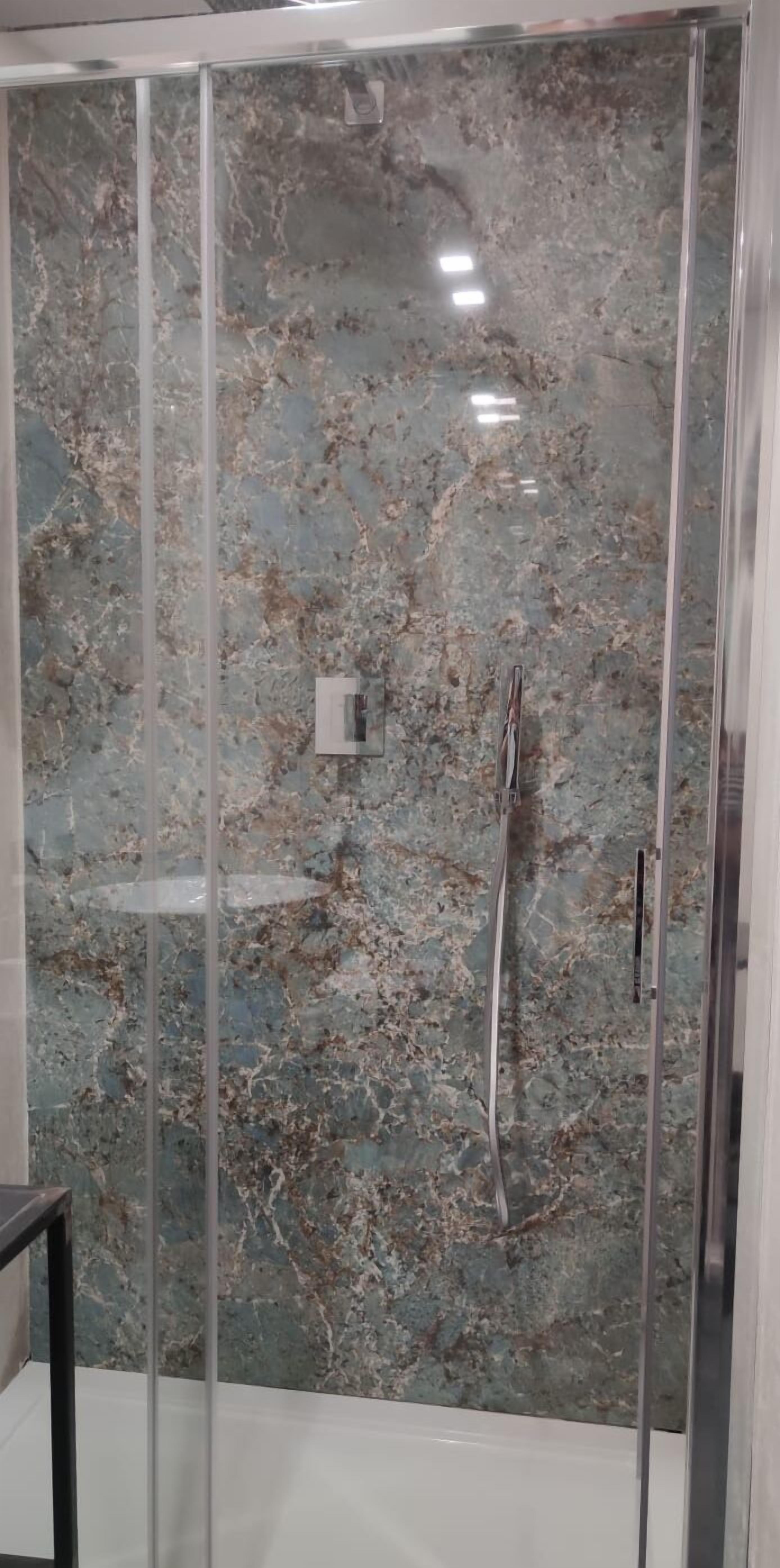 A bathroom with a glass-enclosed shower and a marble wall.