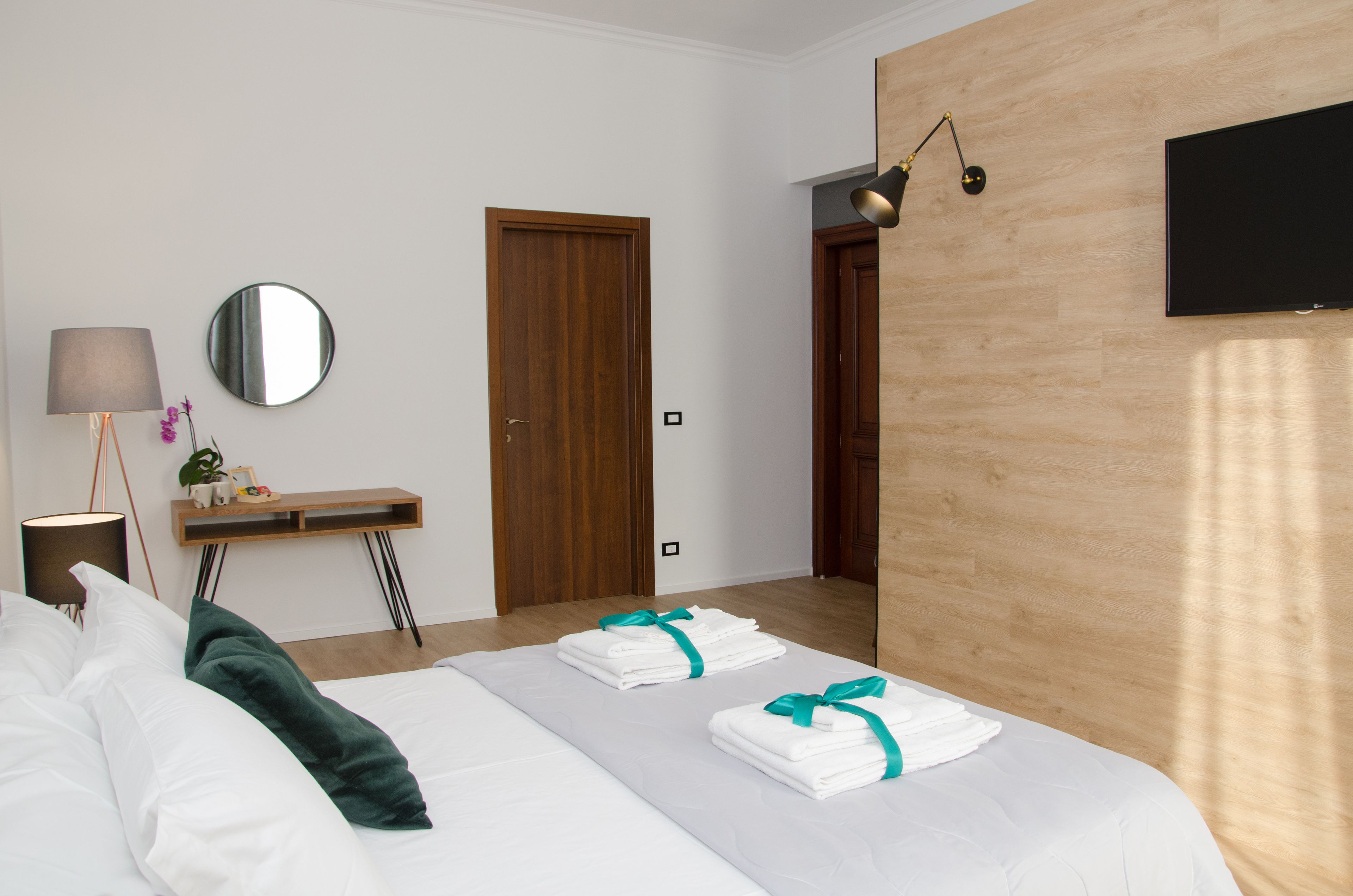 Une chambre d’hôtel avec un lit, un bureau avec une lampe, un miroir et une télévision.