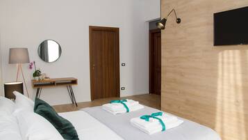 A hotel room with a bed, a desk with a lamp, a mirror, and a TV.