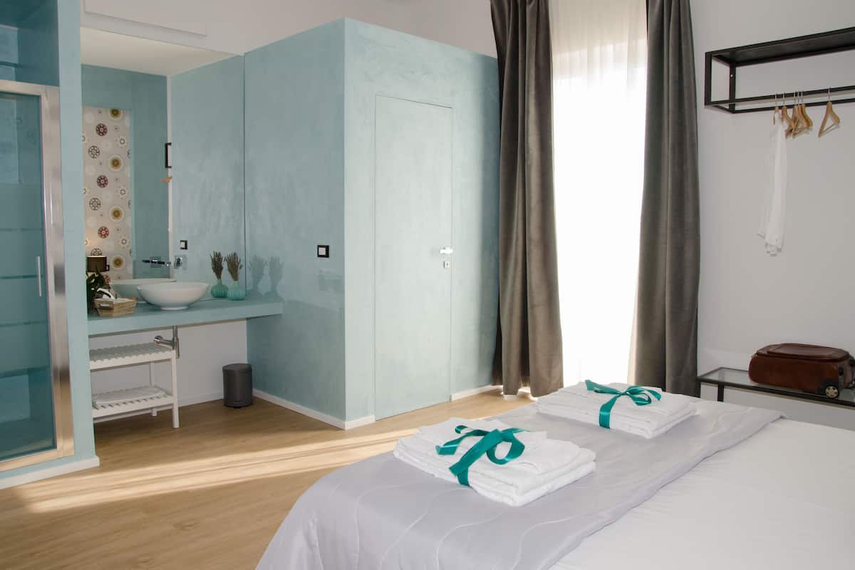 Una habitación de hotel con cama, baño con lavamanos y espejo.