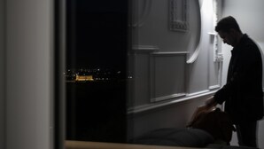 Ein schwach beleuchteter Raum mit einem großen Fenster mit Blick auf eine nächtliche Skyline.