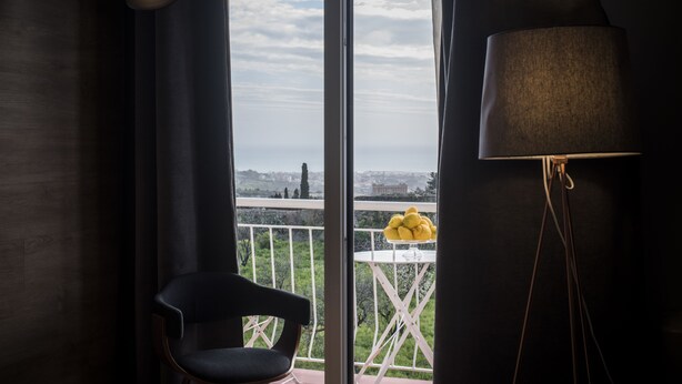 Ein Balkon mit einem Stuhl, einem Tisch mit gelben Blumen und einer Lampe.