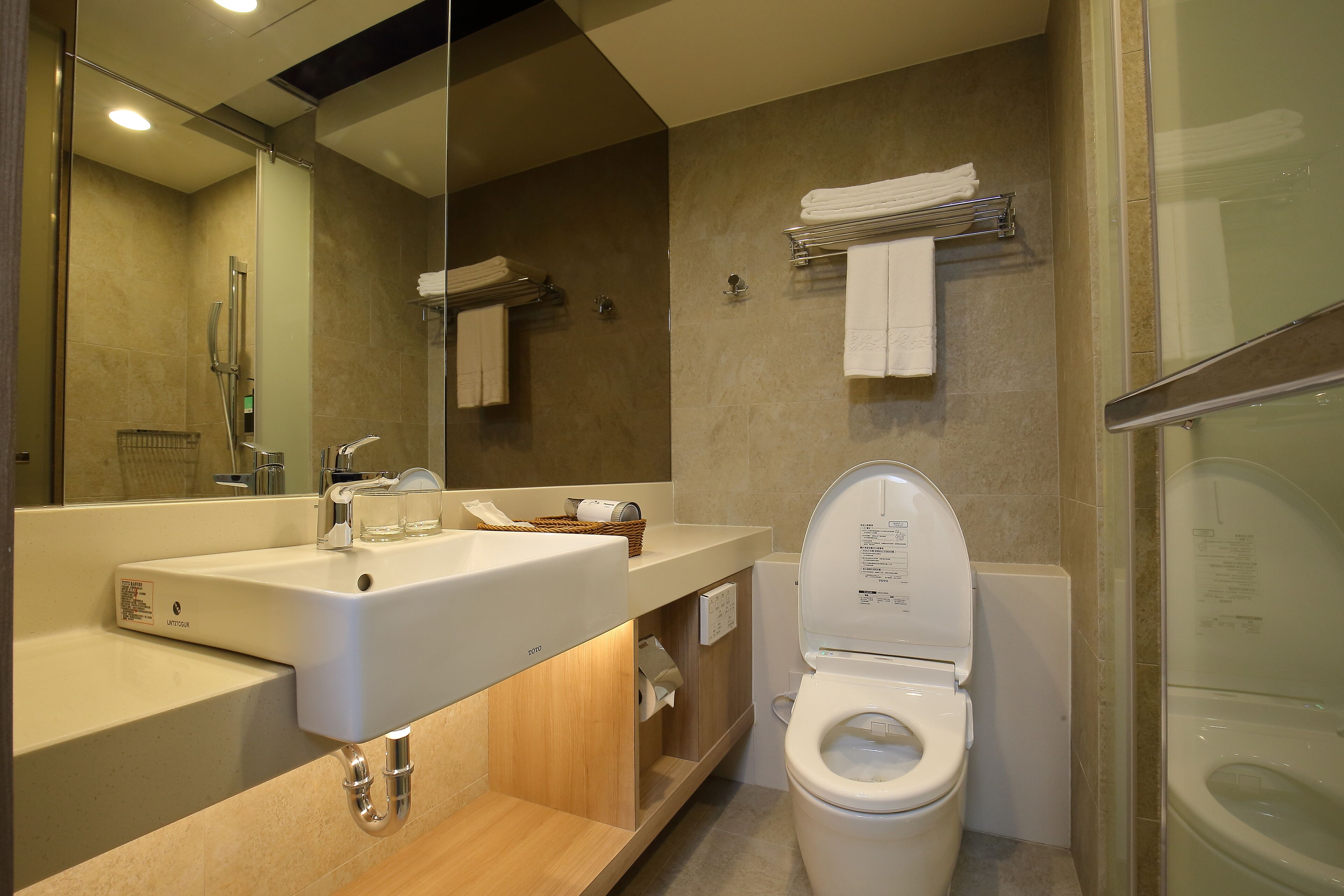 A modern bathroom with a sink, mirror, toilet, and shower area.