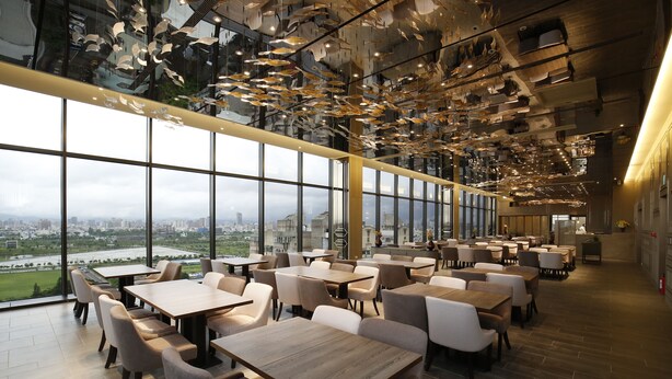 A modern restaurant with large windows offering a city view, wooden tables and chairs, and a unique ceiling design with hanging elements. - Kloud Hotel (Taichung)