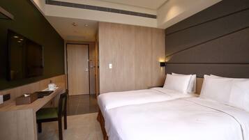 A hotel room with a large bed, a desk with a chair, a flat-screen TV, and a wooden panel wall.