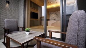 A modern interior with a wooden table and two chairs, a potted plant, and a view of a bathroom through a glass door. - Kloud Hotel (Taichung)