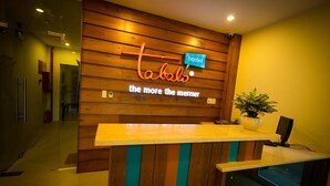 Una recepción con diseño de panel de madera y un letrero de neón que dice "Tabals hostel the more the merrier".
