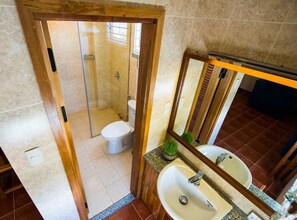 A bathroom with a wooden door, a sink, a mirror, and a toilet. - Tabalo Hostel (Nha Trang)