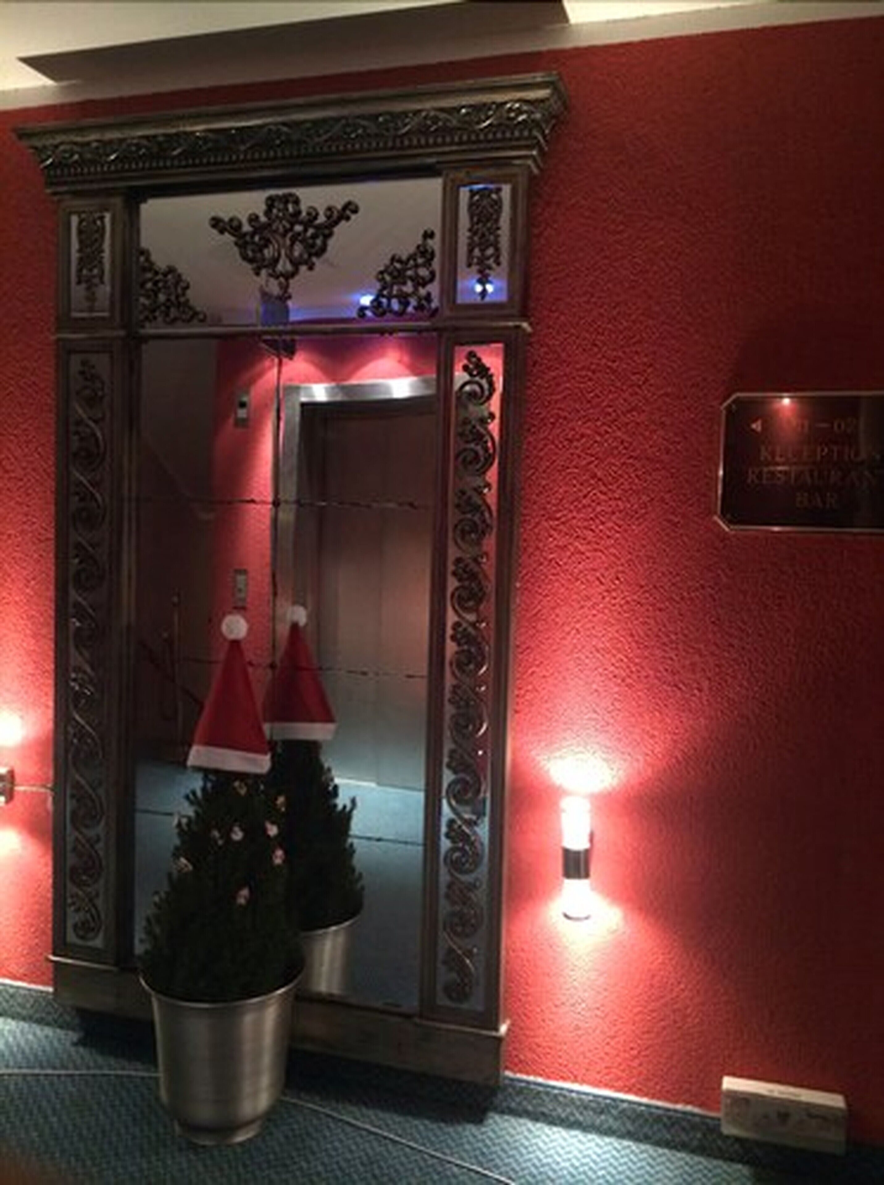 A reception area with a red wall, a reception desk, and two Christmas trees with Santa hats.