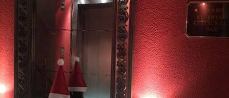 A reception area with a red wall, a reception desk, and two Christmas trees with Santa hats.