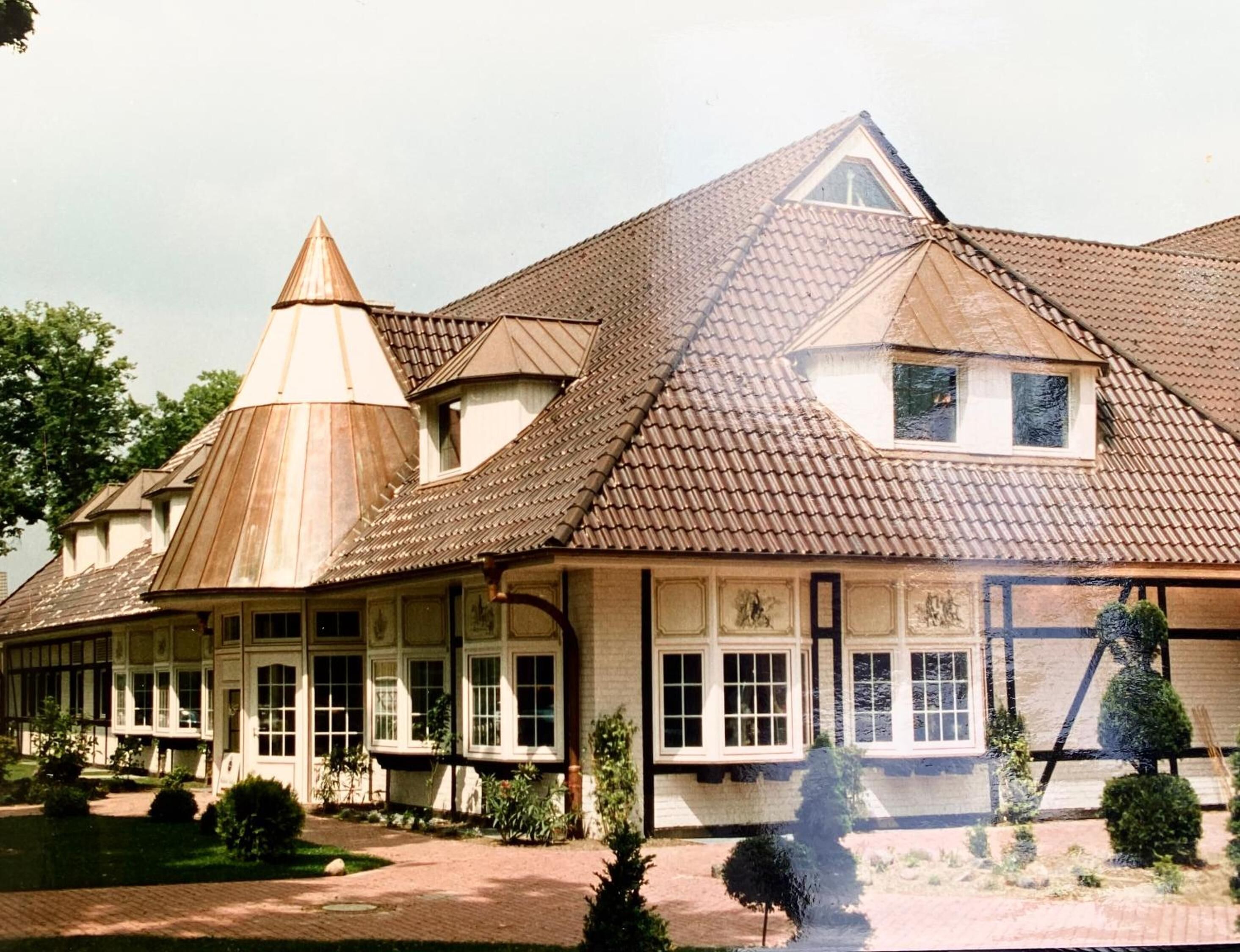 A large, historic building with multiple gabled roofs and a prominent central tower.