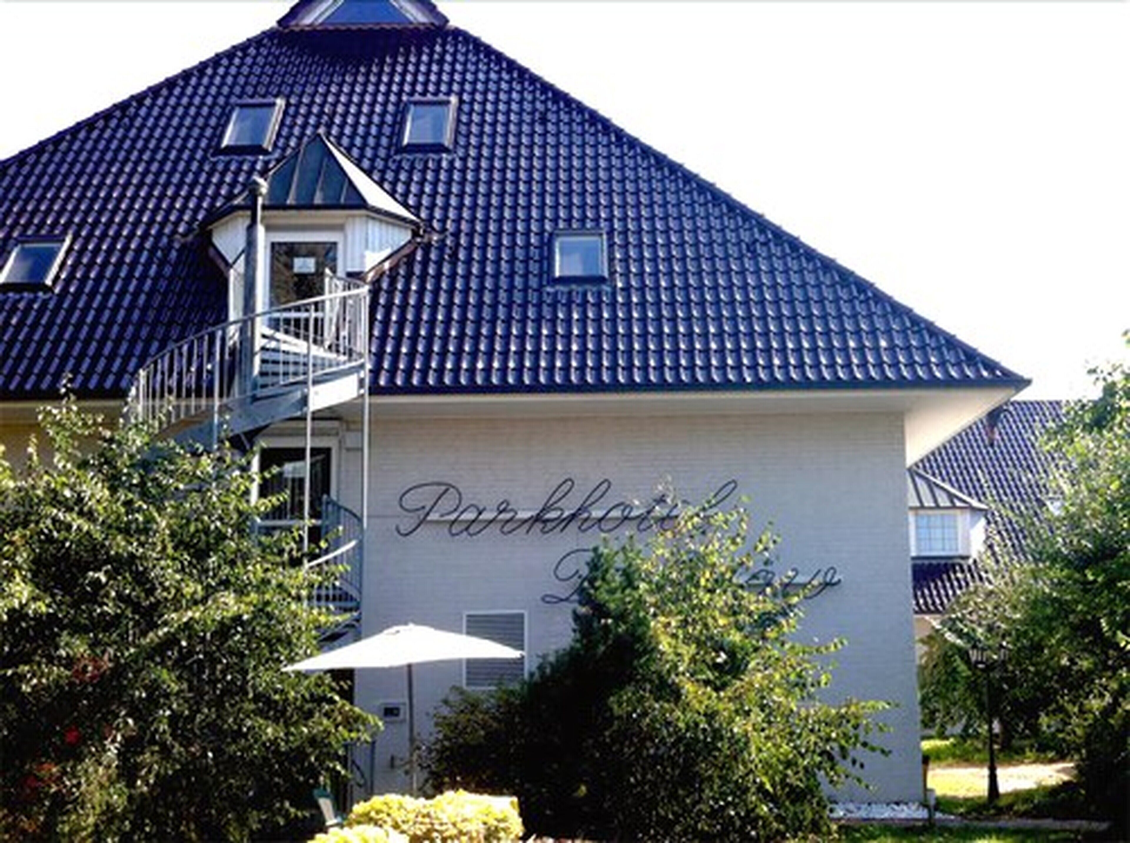 A building with a blue tiled roof and a sign that reads "Parkhotel."