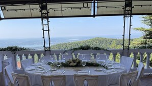 A round table set for six with white tablecloths and chairs, overlooking a scenic view of hills and a distant city. - Albergo Sacro Monte Varese (Varese)
