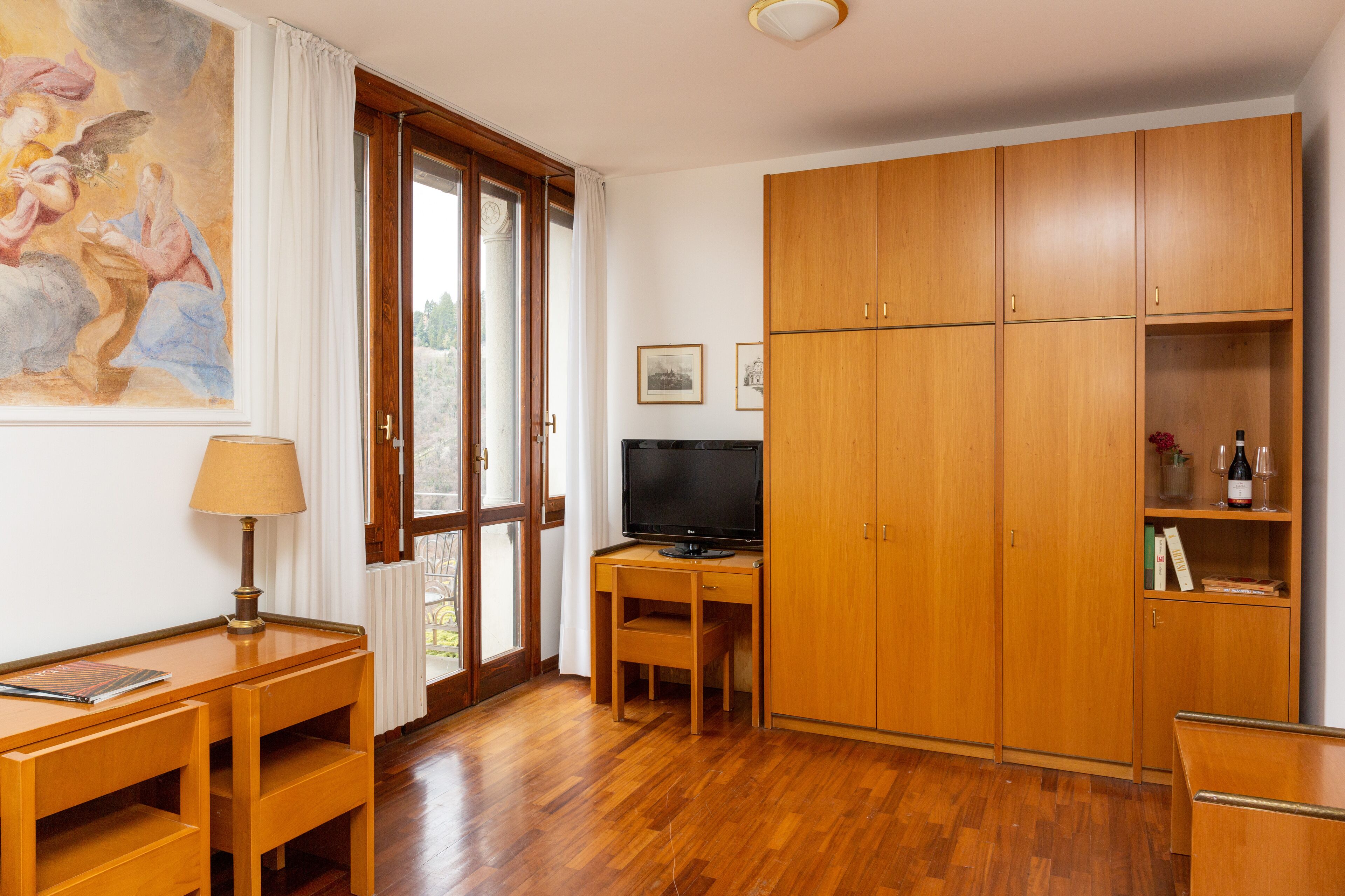 A room with wooden furniture, a television, and a painting on the wall.