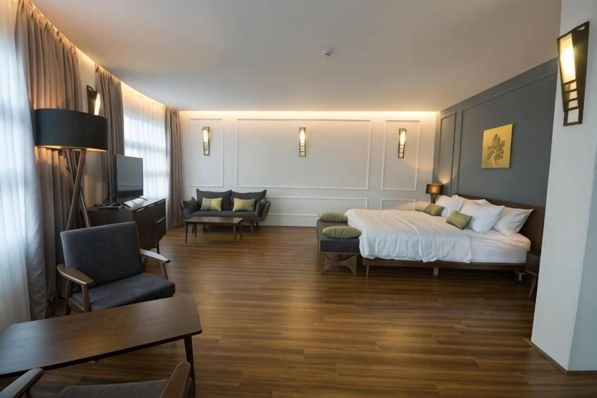Habitación de hotel con cama, escritorio con silla, sofá y televisión.