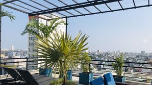 A rooftop terrace with lounge chairs, potted plants, and a city view. - Danang Boutique Hotel (Da Nang)