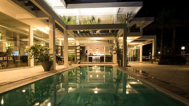A modern hotel with a central pool, outdoor seating, and a bar area. - Danang Boutique Hotel (Da Nang)