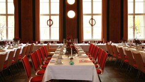 A banquet hall with long tables set for a formal event, large windows with curtains, and a central floral arrangement. - Restaurant Esslust (Niedergoersdorf)