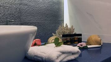 Un baño con un lavamanos blanco, una encimera azul, una toalla blanca, un coral decorativo, una rosa blanca y un cepillo para el cabello.