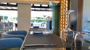 Un restaurant avec une longue table dressée pour le repas, des chaises et un mur décoratif agrémenté d’étagères.
