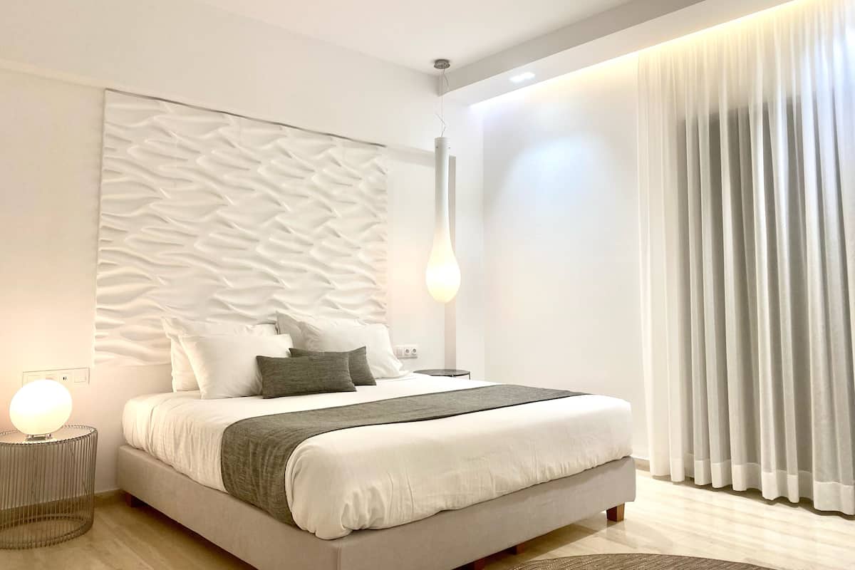 Ein modernes Schlafzimmer mit einem Bett, einer strukturierten Wand, einer Hängeleuchte und einem Fenster mit Vorhängen.