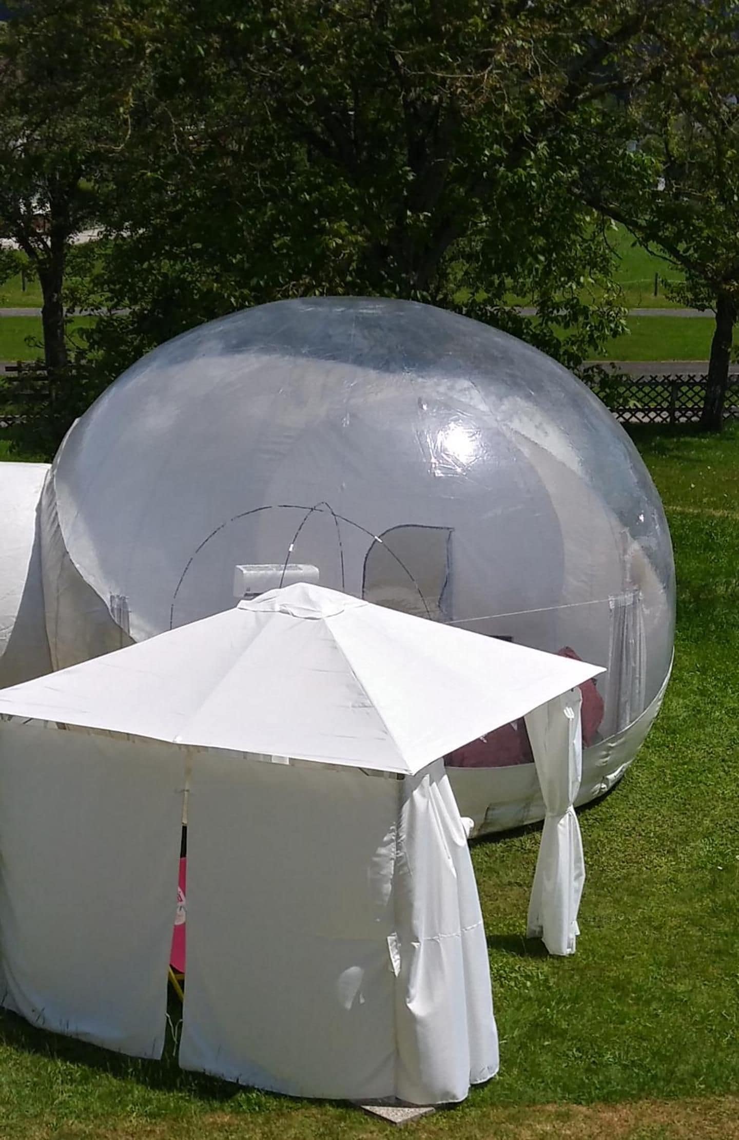 Eine transparente, kugelförmige Struktur mit einem weißen Zelt davor.