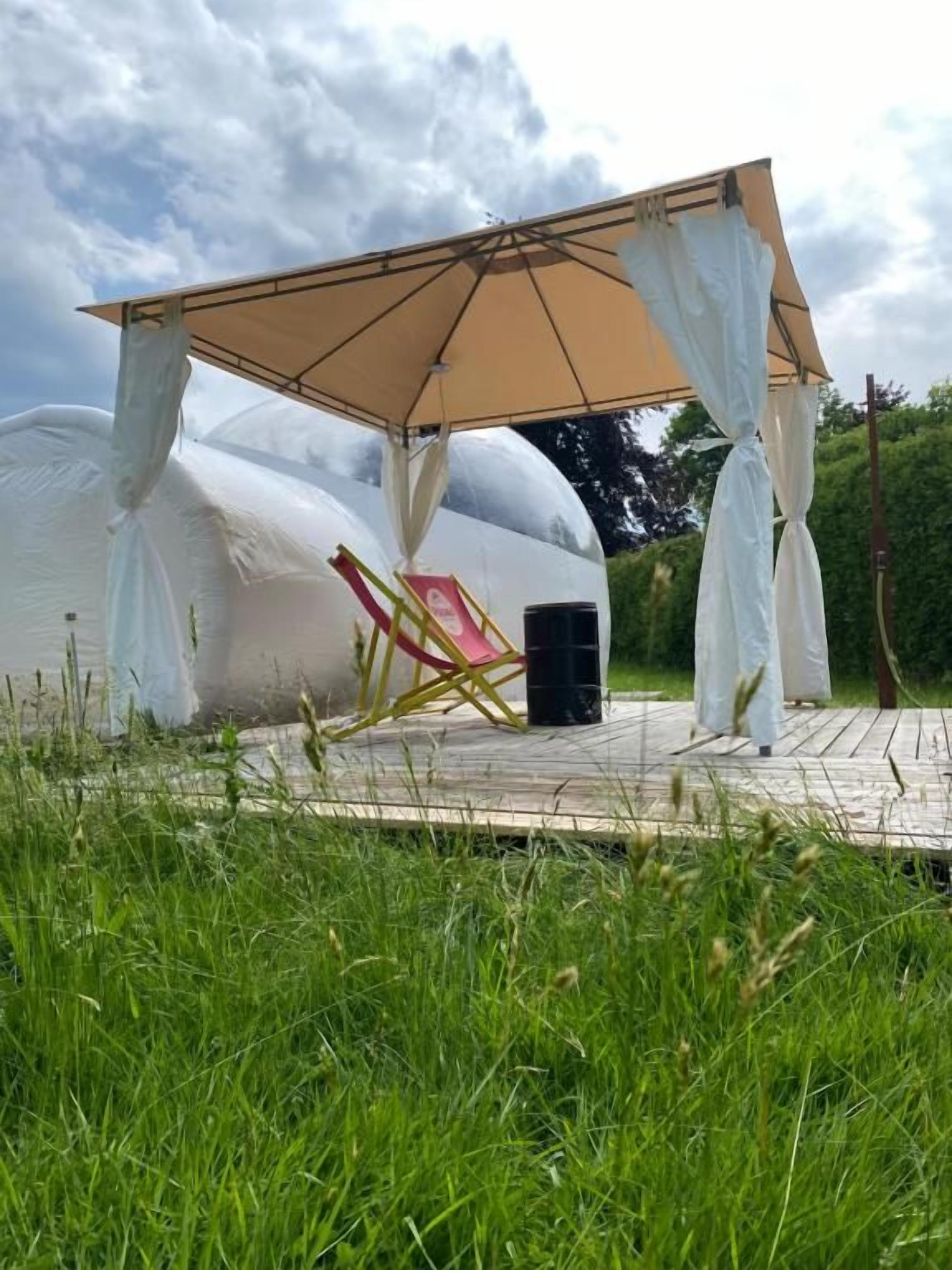 Een overdekt terras met een stoel en een afvalbak.