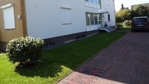 Una casa de dos pisos con fachada de ladrillo, un césped verde y un camino de entrada pavimentado.